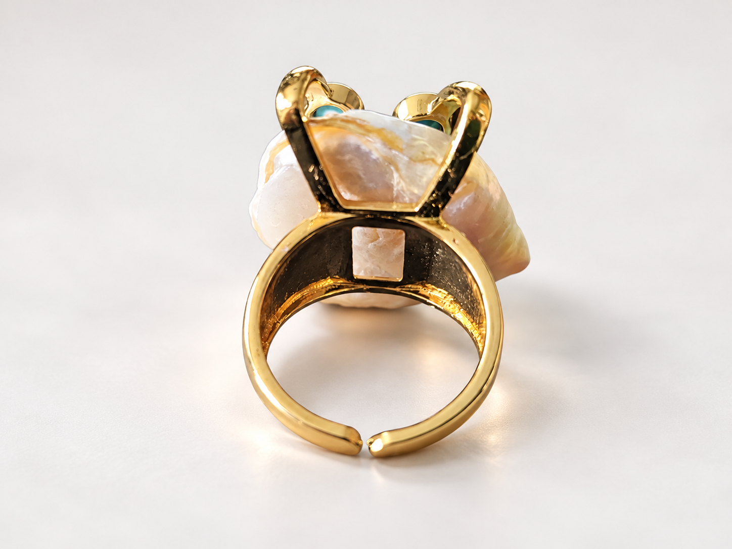 Bague Aurore Irisée aux Cabochons Bleu-Vert — Dos de la bague montrant l’anneau doré ouvert, une découpe rectangulaire dans la monture et l’arrière du motif ivoire irrégulier.