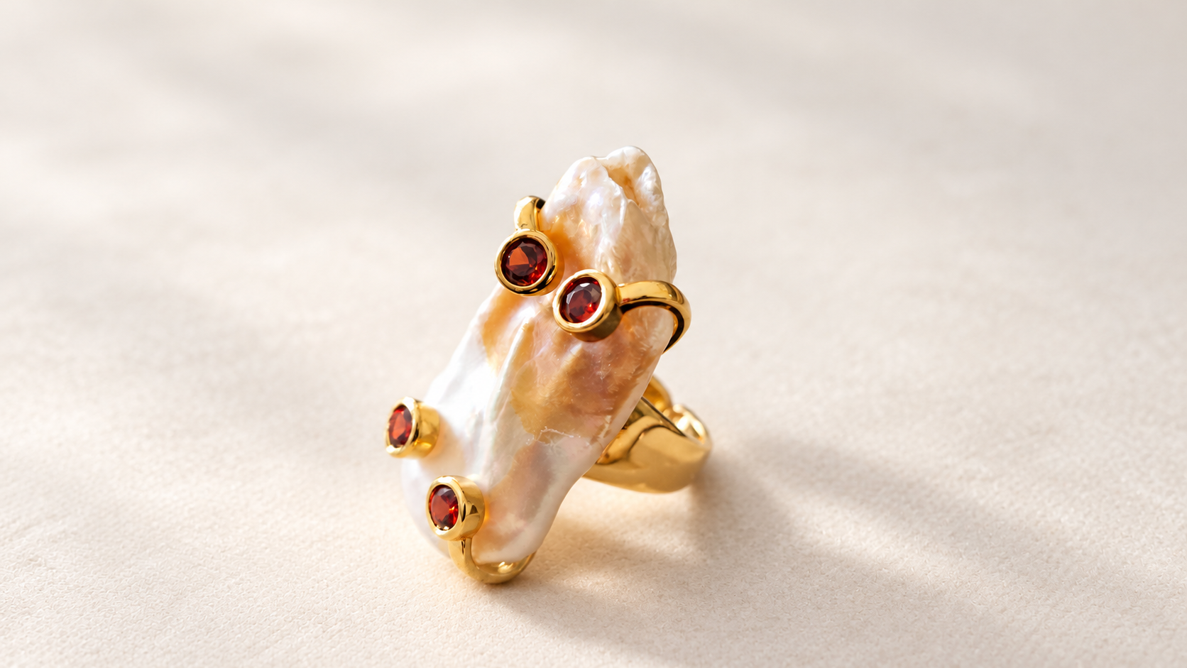 Bague Aurore Baroque aux Accents Rouges — Bague inclinée de trois-quarts, montrant le relief irrégulier du motif irisé, les quatre accents rouges et une partie de l’anneau doré.