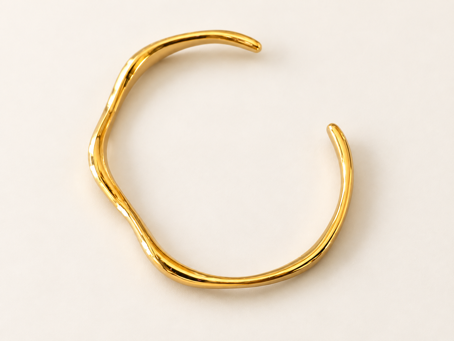 Bracelet Jonc Sillage Doré — Jonc doré disposé en diagonale sur fond clair, ouverture en haut à droite et intérieur lisse apparent.
