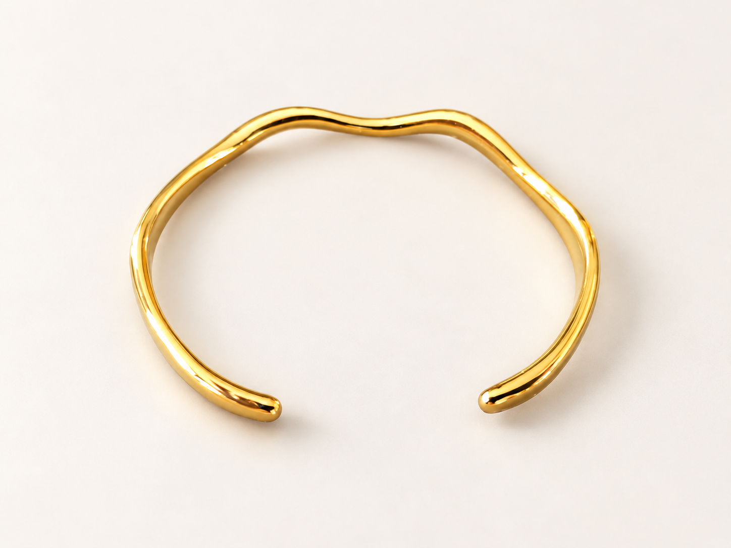 Bracelet Jonc Sillage Doré — Jonc doré vu de dessus, silhouette presque circulaire ouverte en bas et double ondulation sur la partie supérieure.