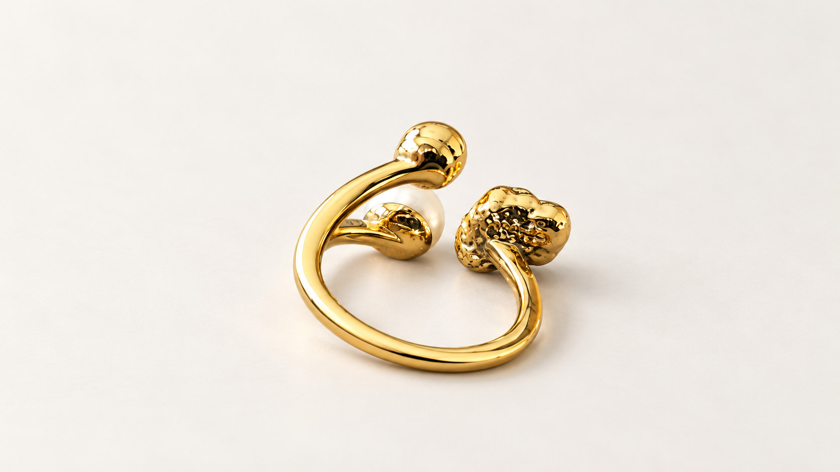 Parure Arabesque — Dos de la bague dorée, avec courbe de l’anneau ouvert et revers des éléments décoratifs ; détail blanc partiellement visible.