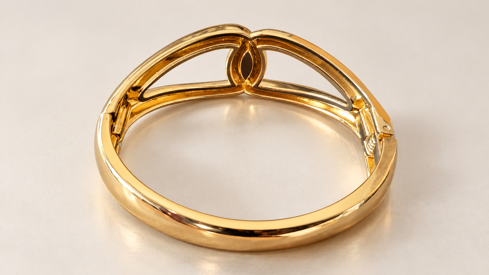 Bracelet Entrelacs Ajouré Doré — Bracelet doré vu depuis l’intérieur, avec l’anneau ovale au premier plan, le revers du motif entrelacé et les éléments d’articulation latéraux visibles.