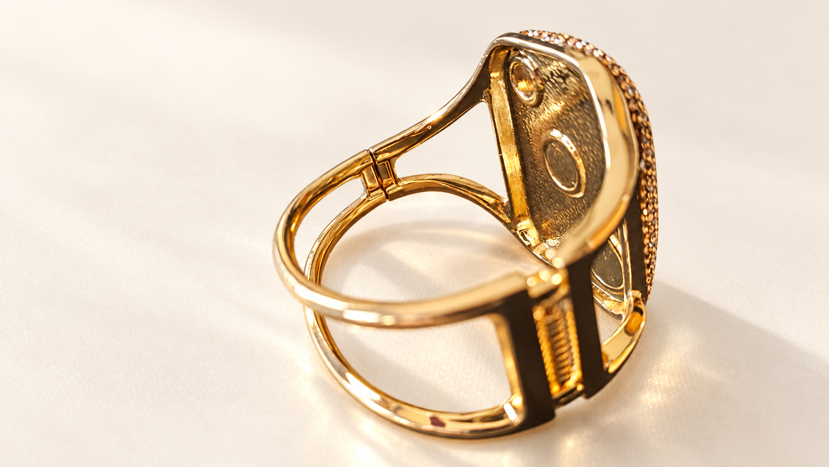 Parure Incandescence Rouge — Intérieur du bracelet doré vu en biais, avec envers texturé du motif, ouvertures circulaires et structure arrière à deux lignes.