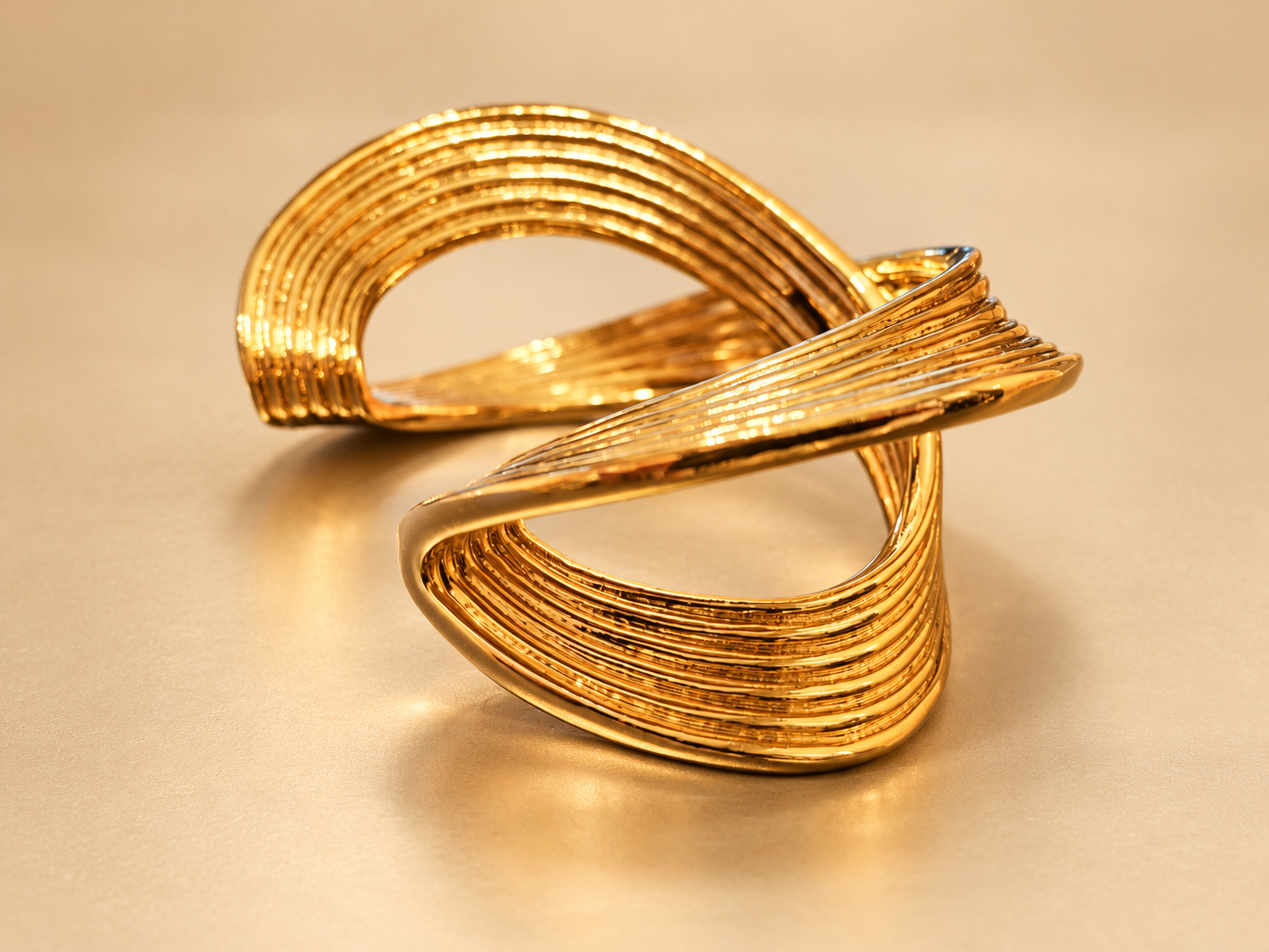 Bracelet Manchette Sillage Croisé Doré — Manchette dorée vue de côté, courbes en relief, stries parallèles et espaces ajourés entre les bandes.