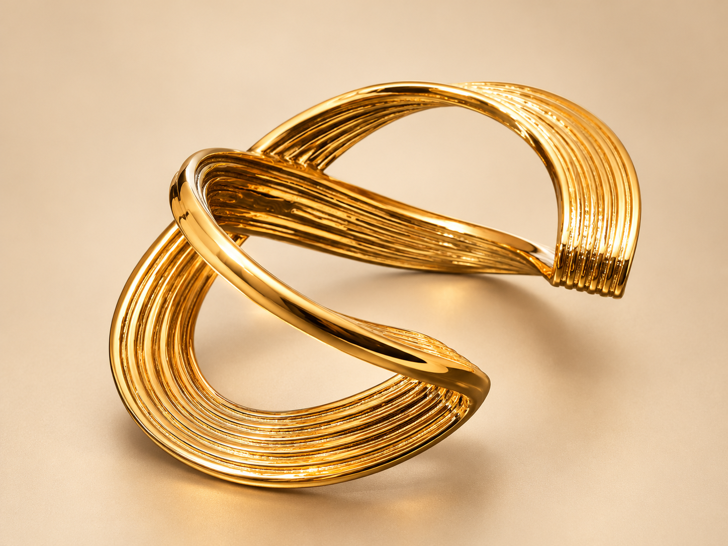 Bracelet Manchette Sillage Croisé Doré — Manchette dorée sous un angle surélevé, courbe lisse au premier plan et surfaces striées autour de larges ouvertures.