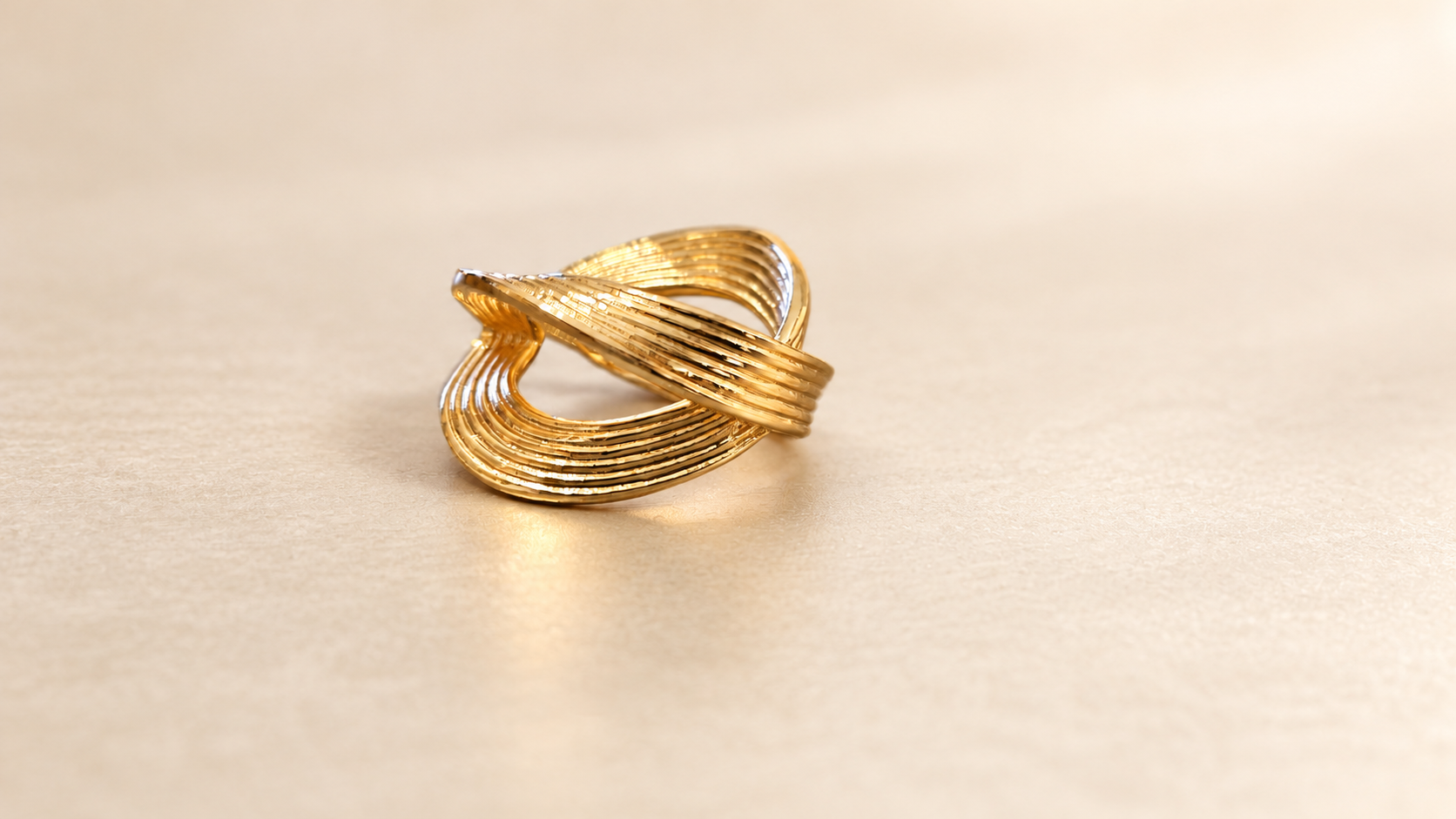 Bague Sillage Croisée Dorée — Bague dorée de trois-quarts, bande diagonale en relief devant une courbe ajourée aux sillons parallèles.
