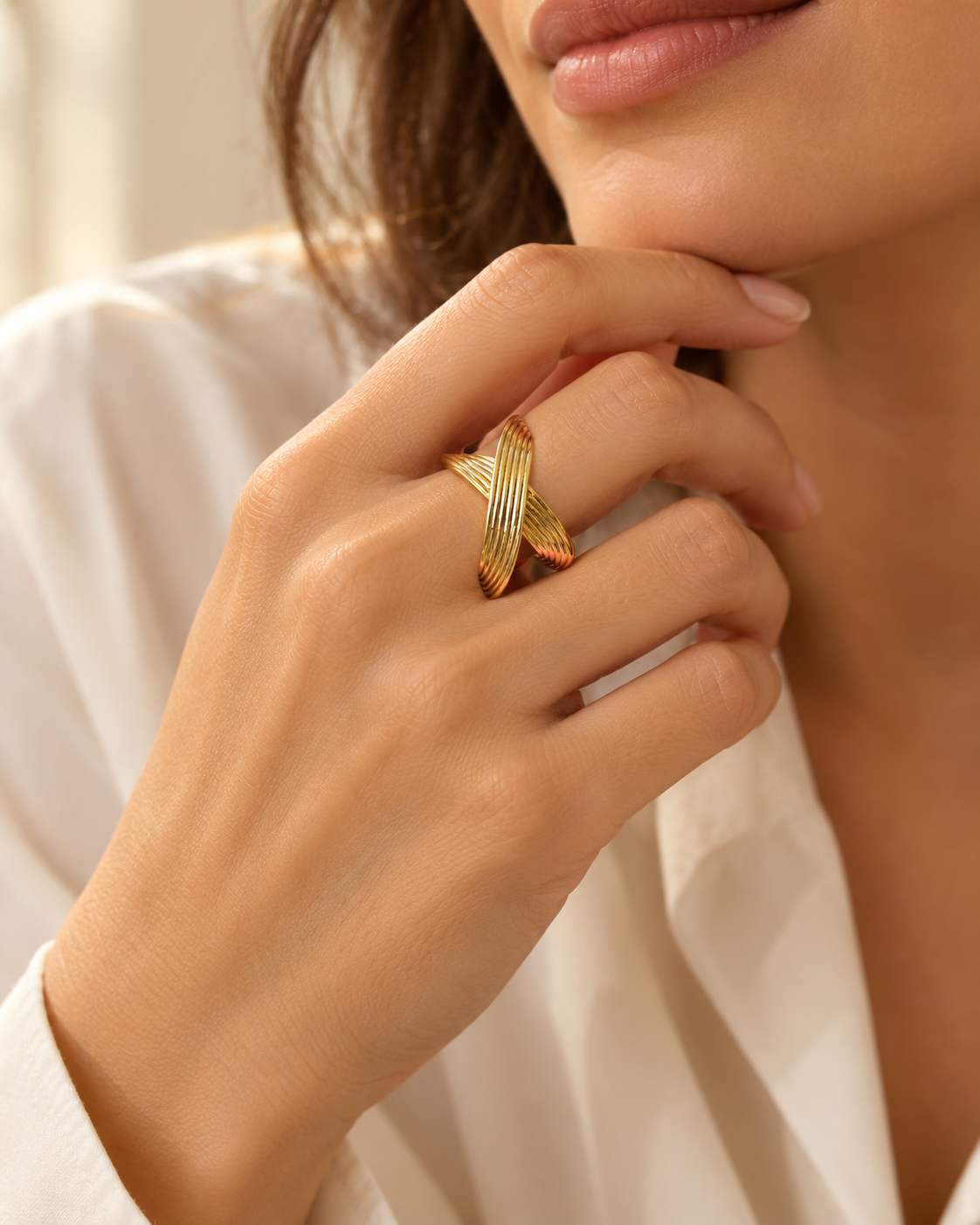 Bague Sillage Croisée Dorée — Bague dorée portée, motif allongé en croix formé de deux rubans courbes parcourus de stries parallèles.