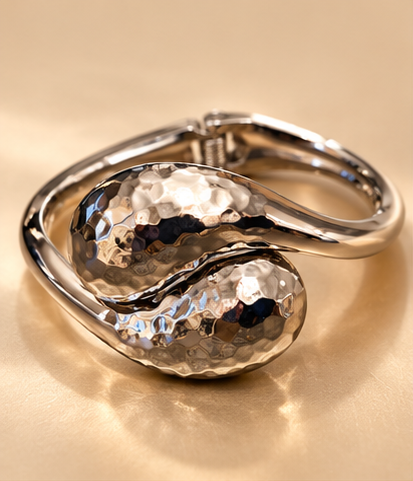 Bracelet Duo Galet — Argenté — Bracelet vu de trois-quarts, avec deux larges extrémités bombées et martelées au premier plan et l’articulation visible à l’arrière.