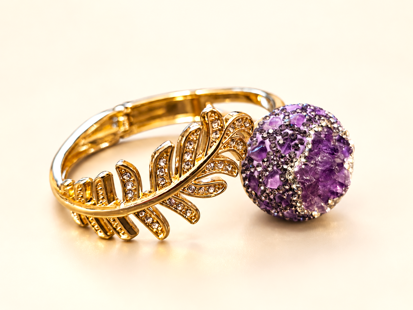 Bracelet de la parure Vesper Ovale Violette — Bracelet posé en biais avec une feuille dorée ornée de détails brillants et une extrémité violette à relief irrégulier.