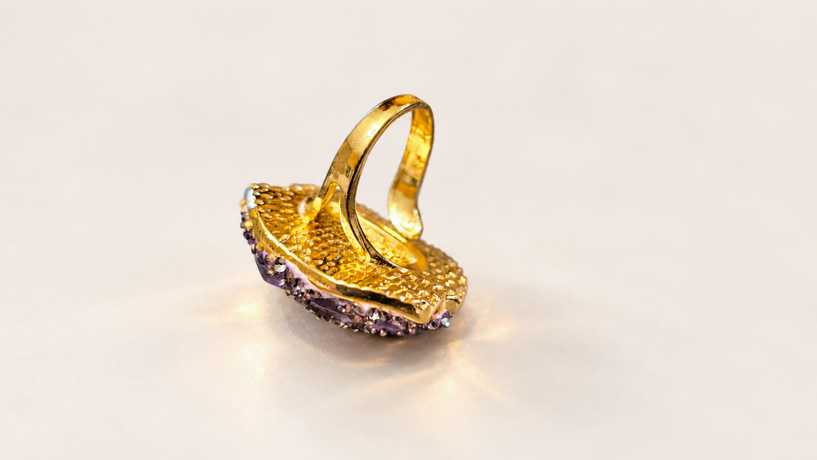 Bague de la parure Vesper Ovale Violette — Dos doré texturé du plateau ovale et intérieur de l’anneau, avec quelques détails violets visibles sur le pourtour.