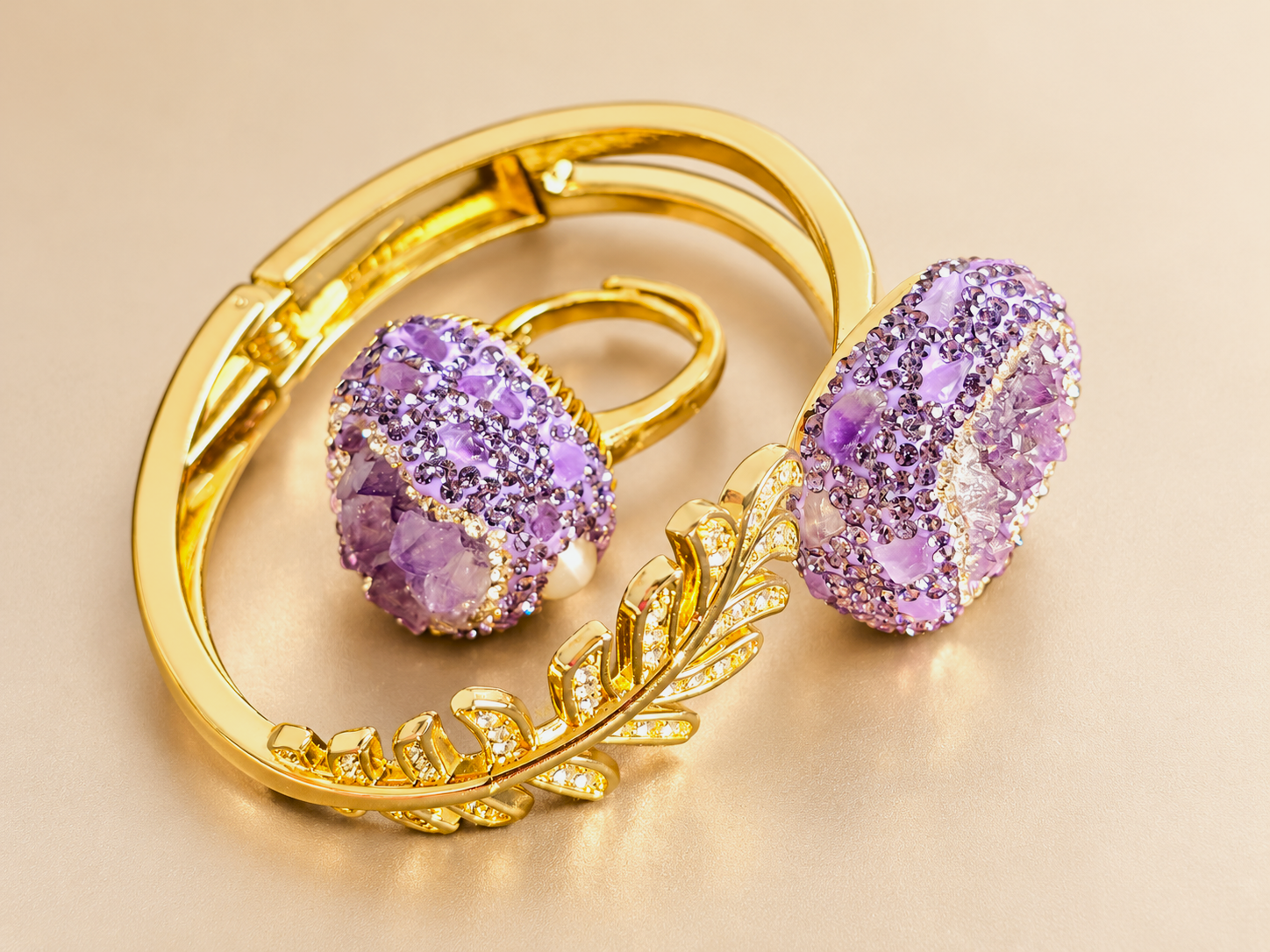 Parure Violette Minérale — Vue plongeante du bracelet doré à motif de feuille et de la bague violette, montrant l’articulation du bracelet et les reliefs des deux décors.