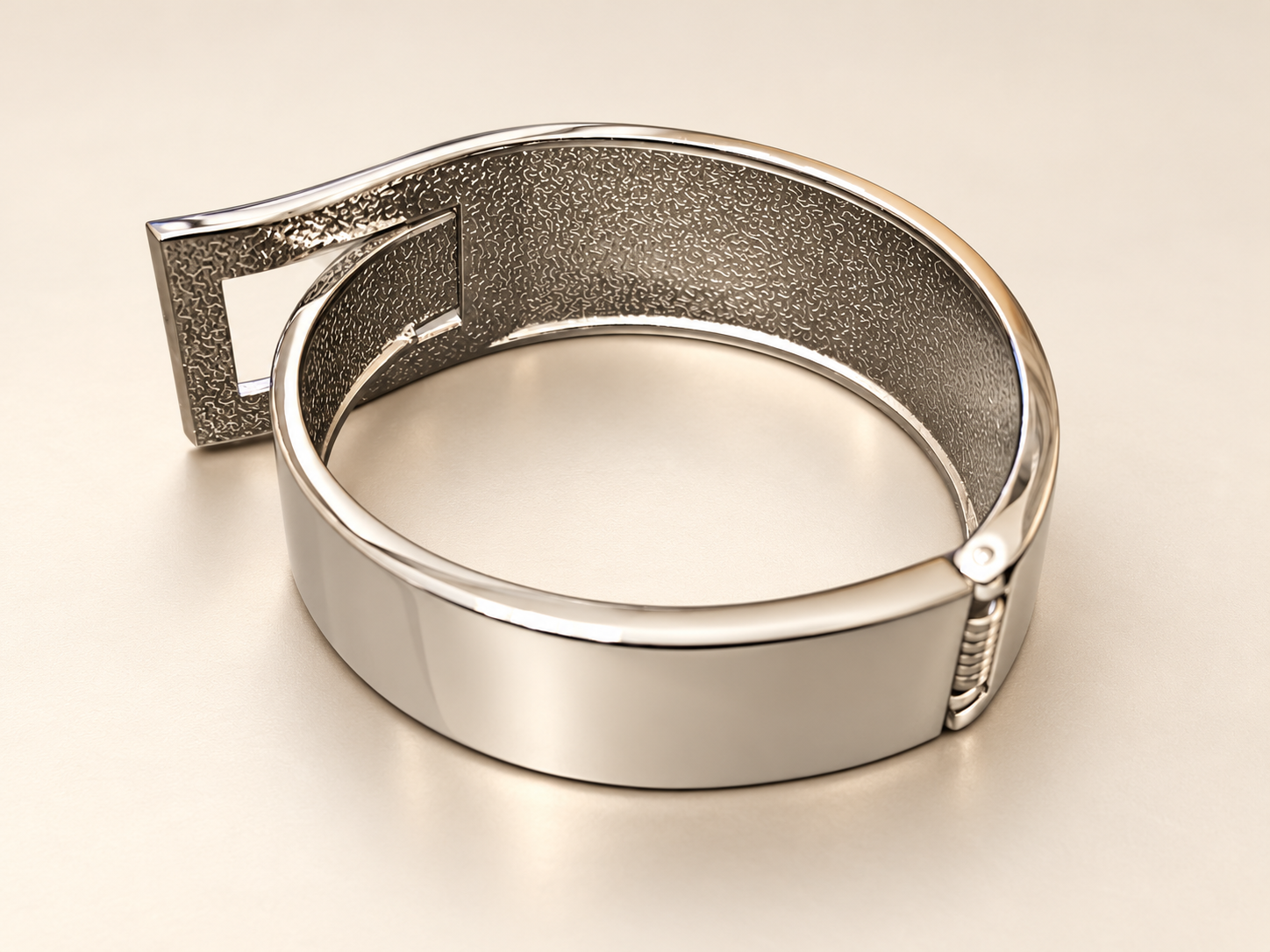 Bracelet Manchette Passage Argenté — Vue oblique de l’intérieur texturé de la manchette argentée, avec charnière à droite et revers du cadre ajouré à gauche.