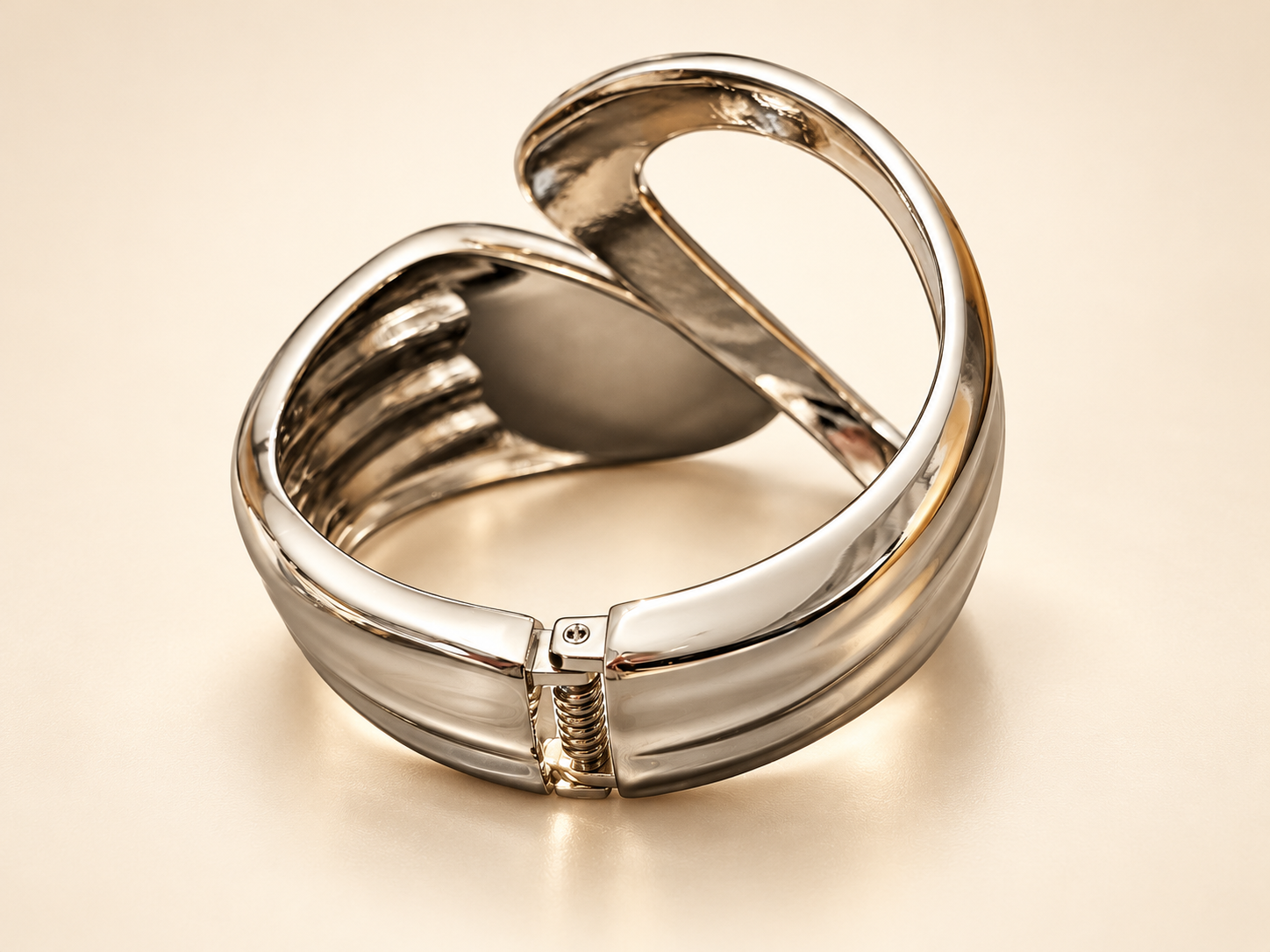 Bracelet Volute Ajouré — Dos du bracelet sur fond clair, charnière à ressort au premier plan et intérieur des courbes ajourées visible.