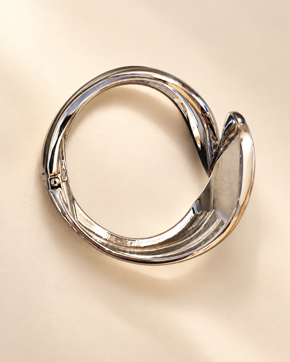 Bracelet Volute Ajouré — Bracelet vu de dessus, contour ovale, extrémités asymétriques et charnière visible sur le côté gauche.