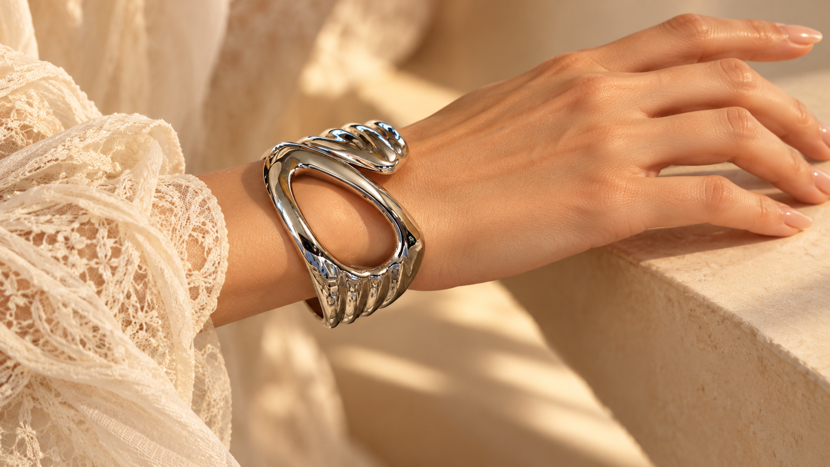 Bracelet Volute Ajouré — Bracelet porté au poignet, grande ouverture arrondie sur le devant et plis bombés aux reflets argentés.