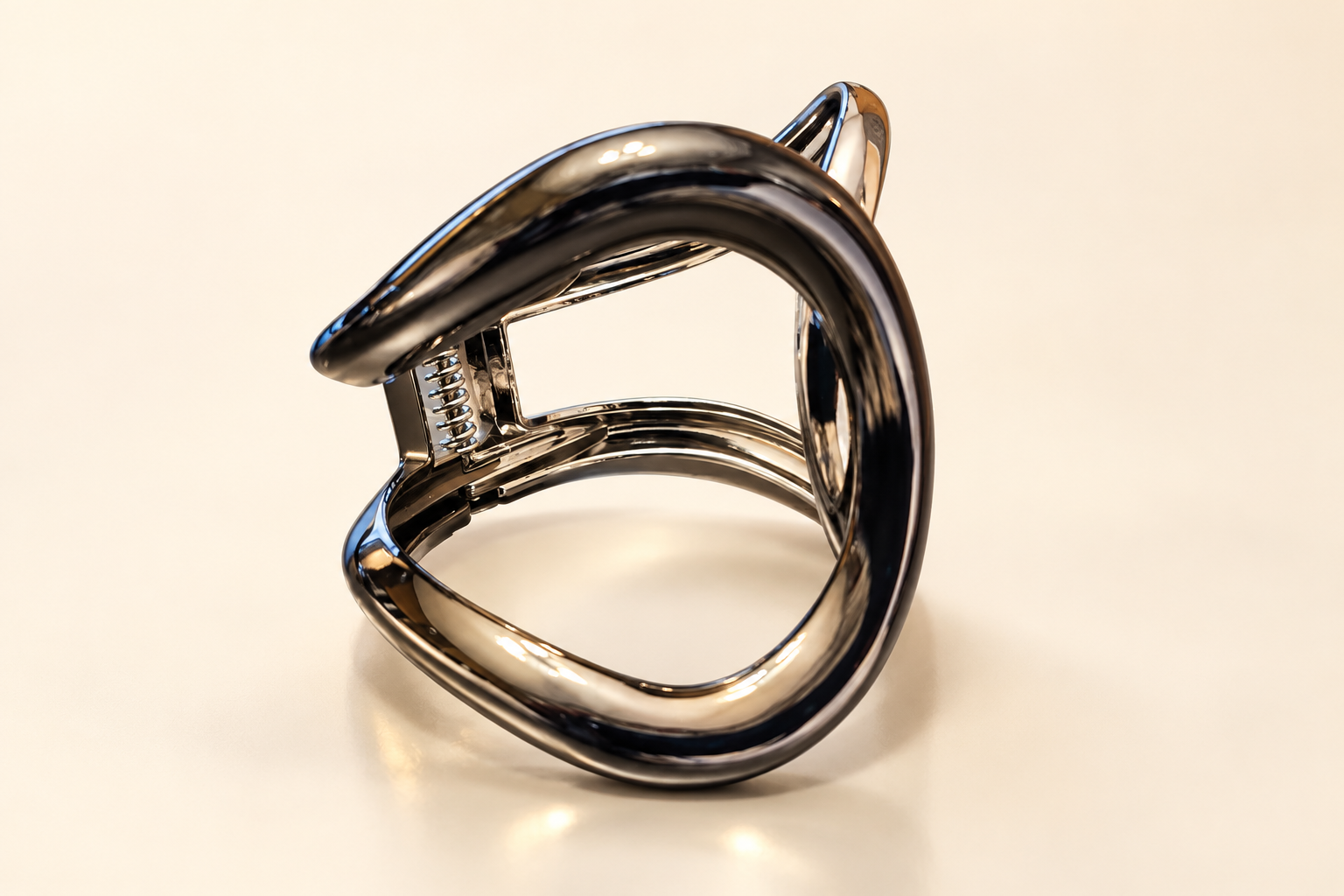 Bracelet Manchette Arabesque aux Courbes Miroir — Bracelet vu de profil, grande courbe arrondie au premier plan et articulation à ressort visible sur le côté gauche.