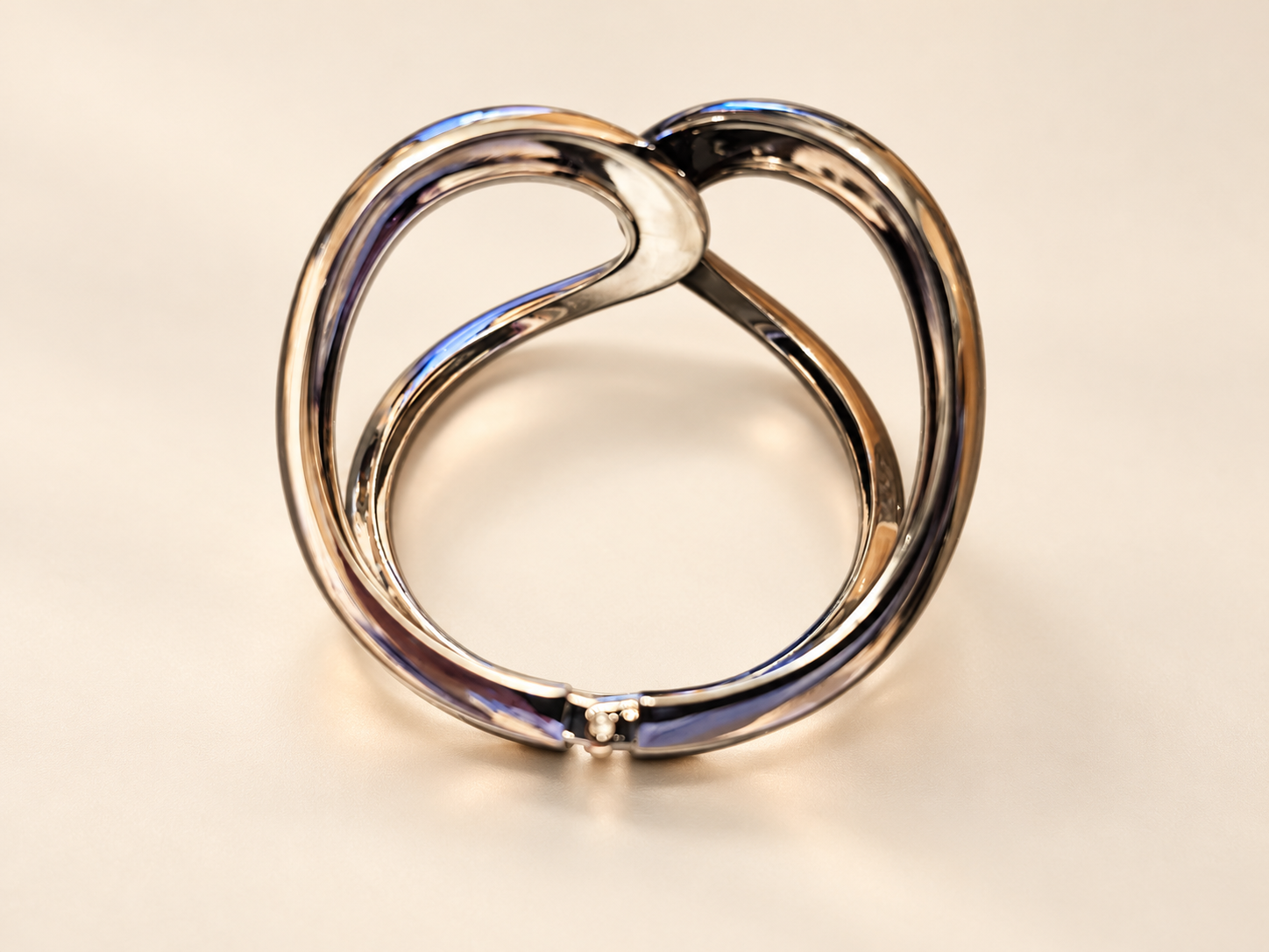 Bracelet Manchette Arabesque aux Courbes Miroir — Vue dans l’ouverture du bracelet, contours arrondis croisés en partie haute et jonction articulée visible au premier plan.