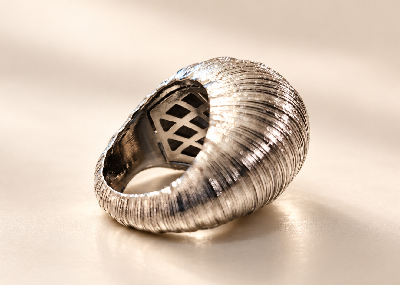 Bague Sillage Bombée Argentée — Bague argentée vue de trois-quarts depuis le côté opposé, avec anneau ouvert au regard et relief bombé strié.