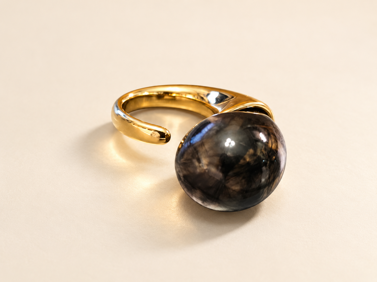 Bague Brume Cabochon Fumé — Bague de trois-quarts avec cabochon bombé gris fumé au premier plan et anneau ouvert doré à l’arrière.