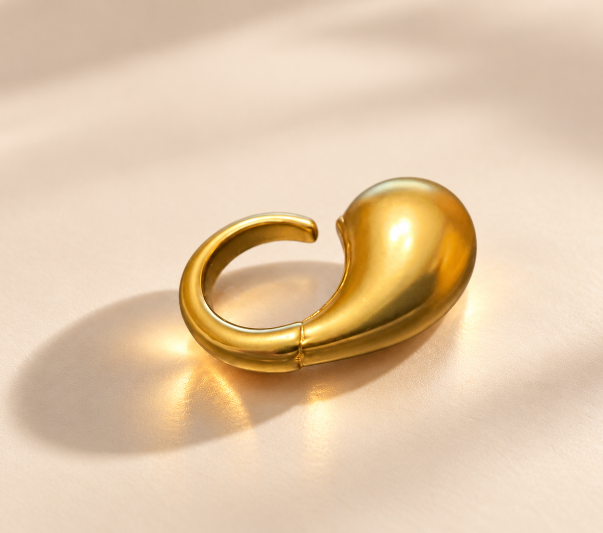 Bague Fluidité Goutte Bombée — Doré — Bague doré vue de côté, goutte allongée à droite et courbe ouverte de l’anneau à gauche.