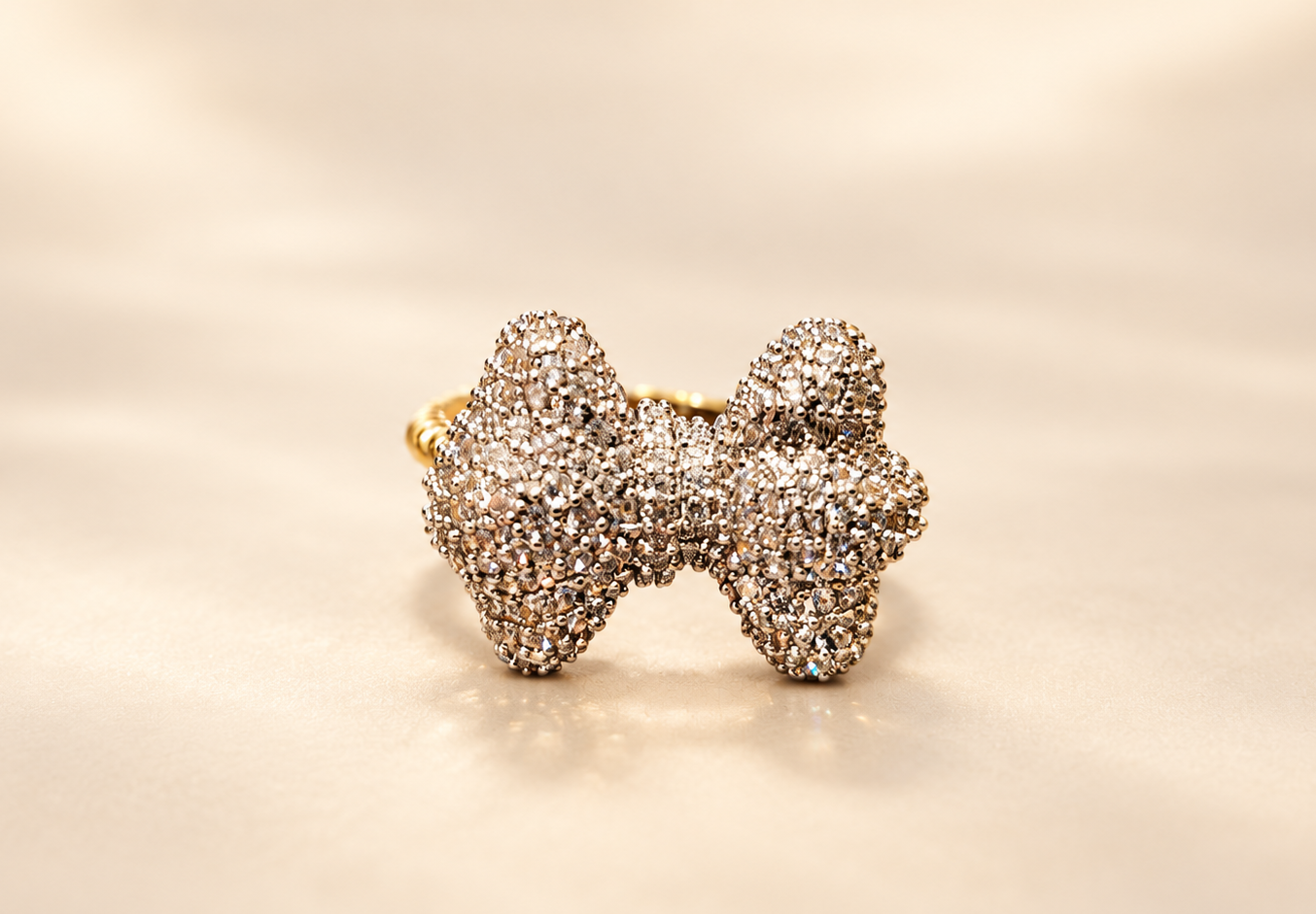 Bague Révérence Nœud Scintillant — Nœud vu de face, aux deux boucles bombées couvertes de petits éléments brillants, avec un aperçu de l’anneau doré derrière.