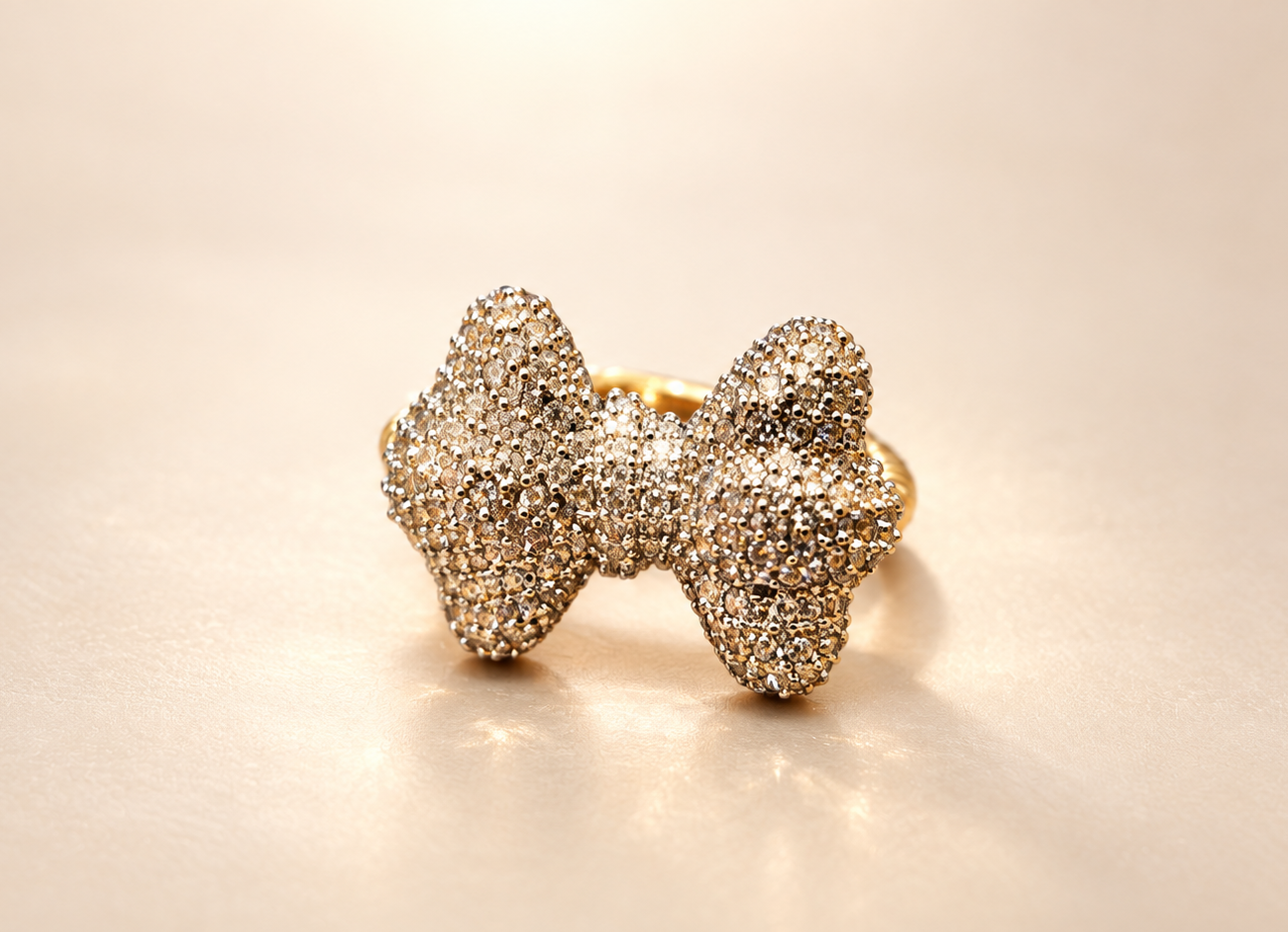 Bague Révérence Nœud Scintillant — Nœud légèrement incliné montrant le volume des boucles, le centre resserré et les reflets clairs et champagne de sa surface.