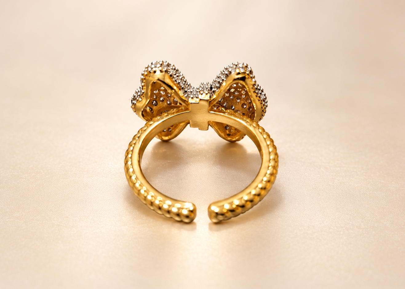 Bague Révérence Nœud Scintillant — Dos doré et ajouré du nœud, avec l’intérieur lisse de l’anneau et ses deux extrémités ouvertes à l’arrière.
