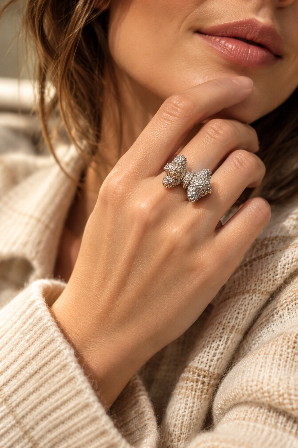 Bague Révérence Nœud Scintillant — Bague portée, montrant le nœud en relief aux éclats argentés et une petite portion de l’anneau doré.
