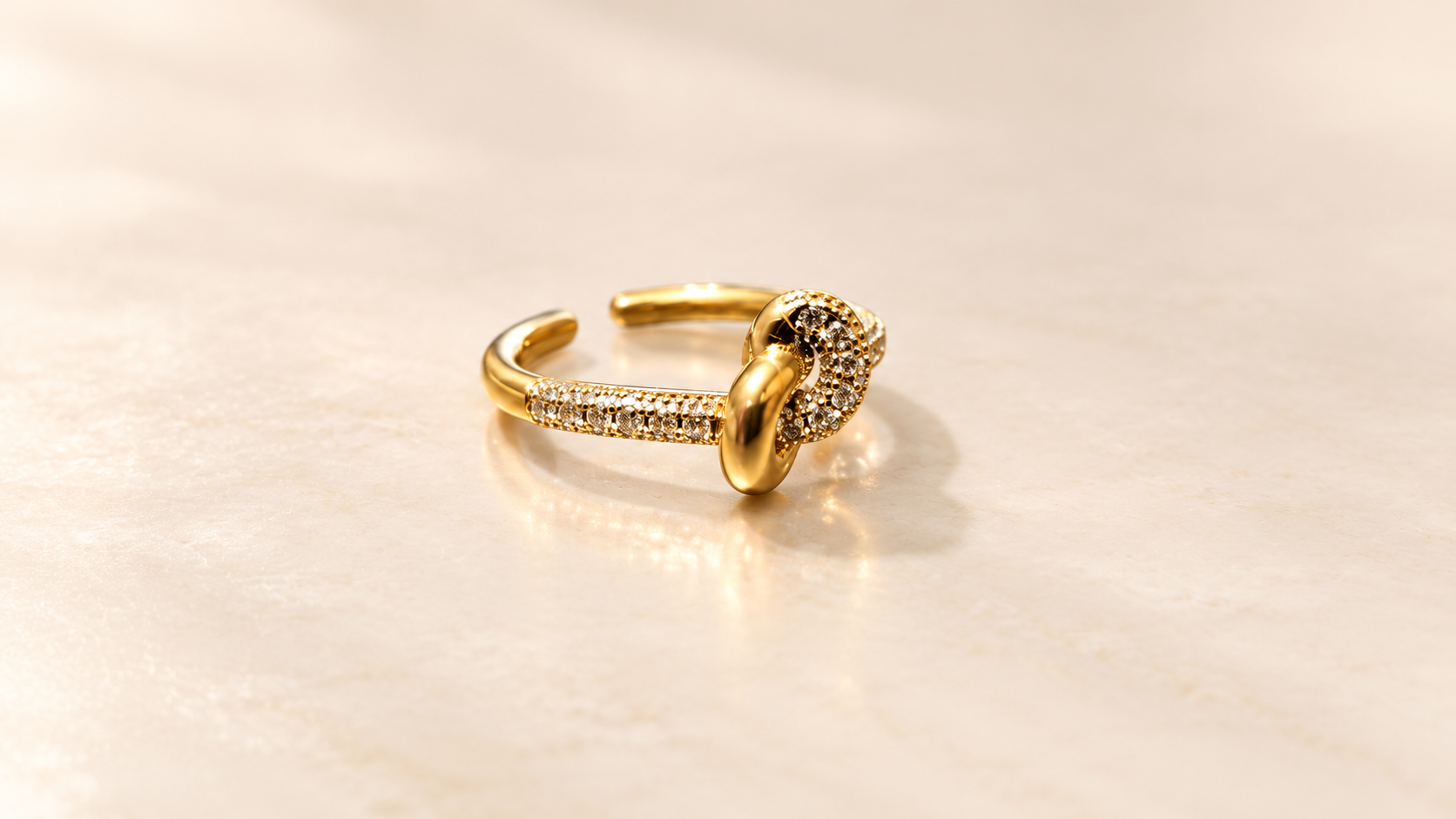 Bague Complicité Nouée | Dorés — Bague dorée vue de trois-quarts, montrant le relief des boucles entrelacées et les éléments brillants sur le côté de l’anneau.