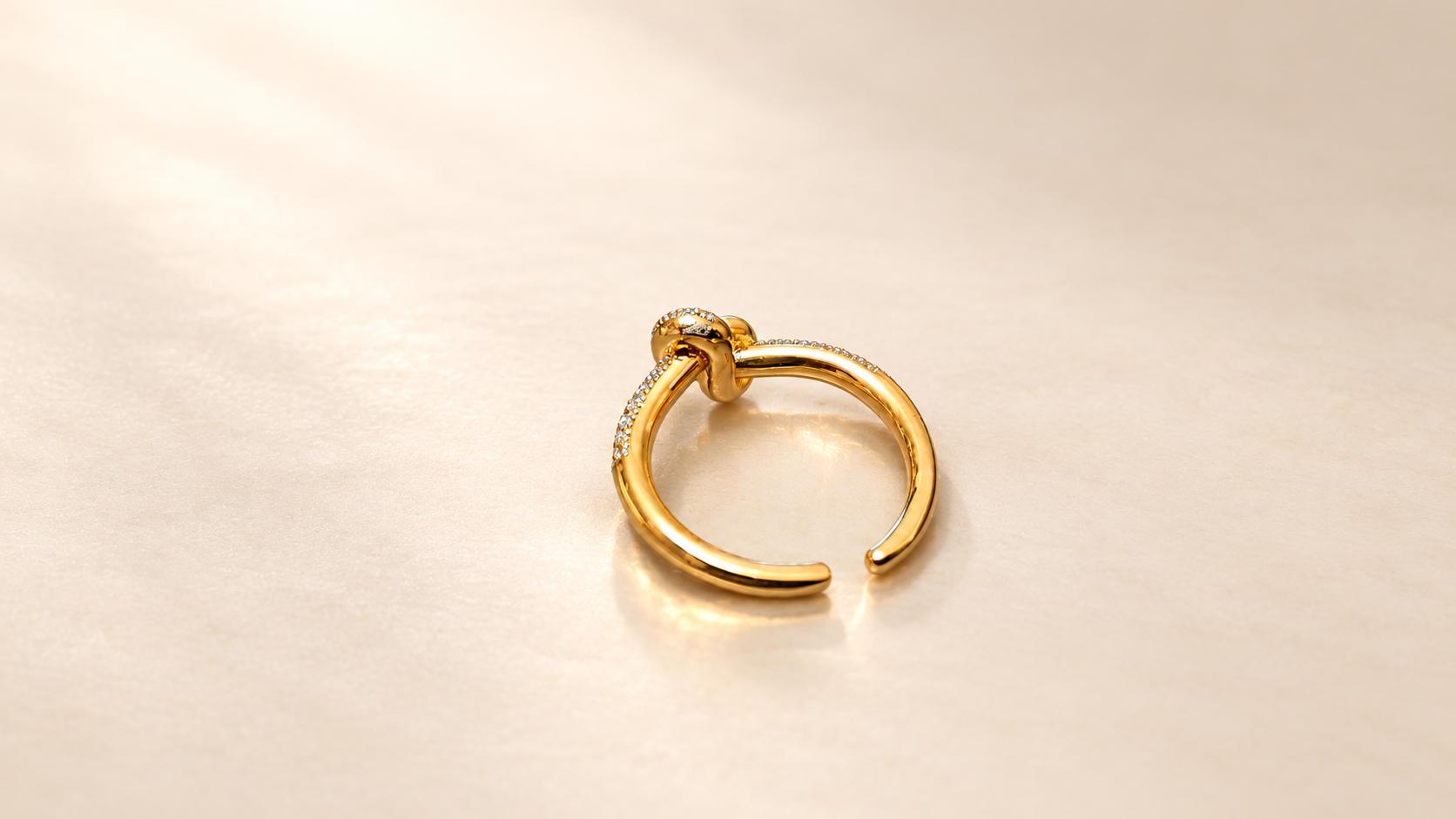 Bague Complicité Nouée | Dorés — Bague dorée vue depuis l’arrière en biais, montrant l’anneau ouvert, ses surfaces lisses et le revers du motif central.