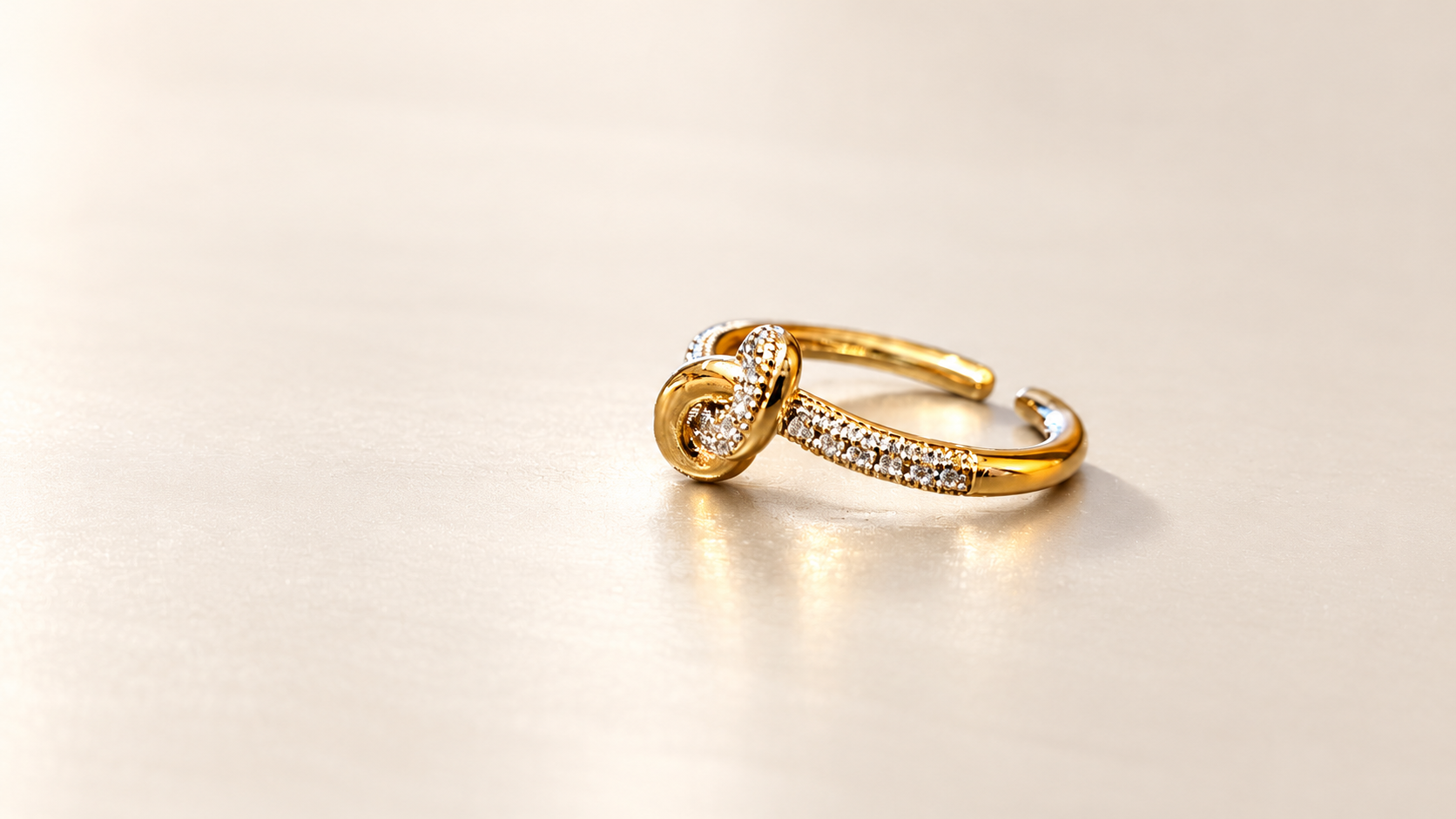 Bague Complicité Nouée | Dorés — Vue oblique de la bague dorée, avec boucle lisse au premier plan, boucle brillante entrelacée et ouverture de l’anneau à droite.